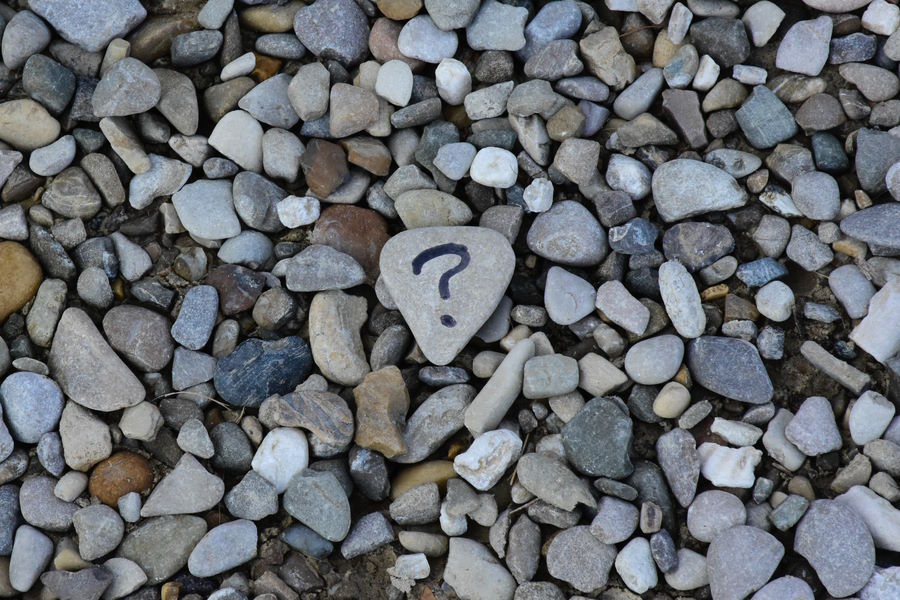 Pebbles on a beach, one with a question mark in black marker pen