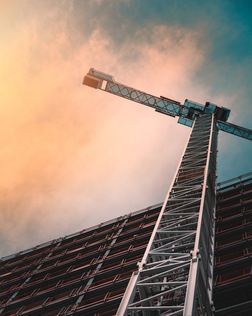 Ground-level view looking up at a tower crane on a construction site