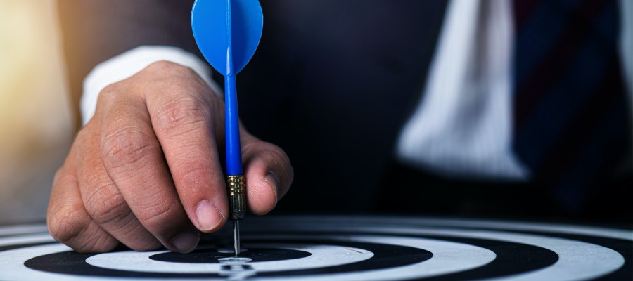 A businessman puts a plastic dart into the bullseye on a dartboard